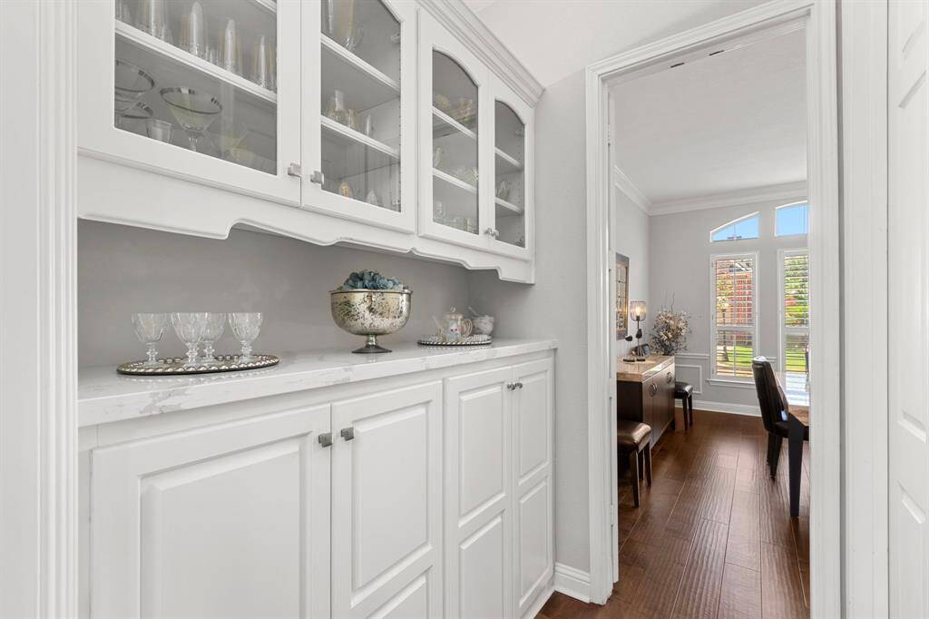 The butler's pantry offers custom cabinetry with pull-out shelving with quartz countertop and pretty glass front upper cabinets. This is a perfectly situated for hosting fabulous gatherings and dinners!