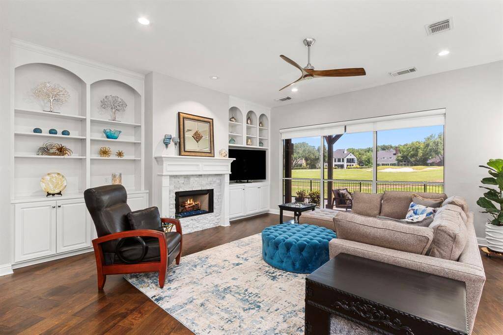The stunning family room is spacious with a gas log fireplace surrounded on either side by custom built-ins. The designer ceiling fan is perfect, and the wall of windows with remote control blinds provide unparalleled views of the 4th hole of the Pecan Course of Sweetwater Country Club's prestigious course.