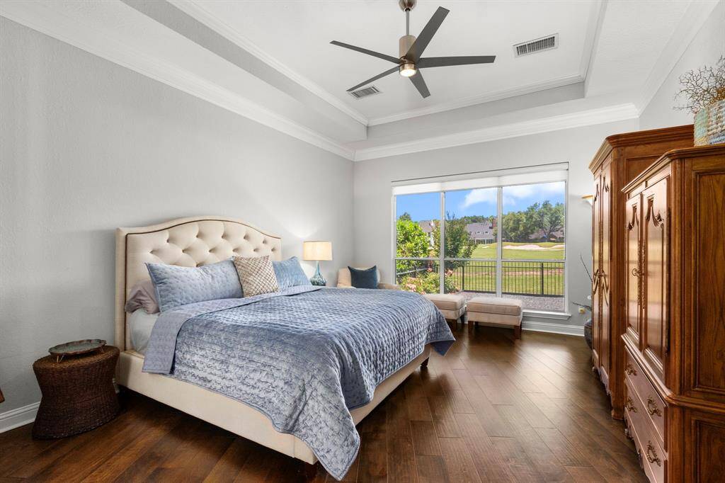 The pretty primary bedroom is large with beautiful tray ceilings and deep crown molding. The flooring has the same engineered hardwoods that runs expansively throughout the first floor. The wall of windows offers great views of the backyard and golf course and are completed with remote control blinds.