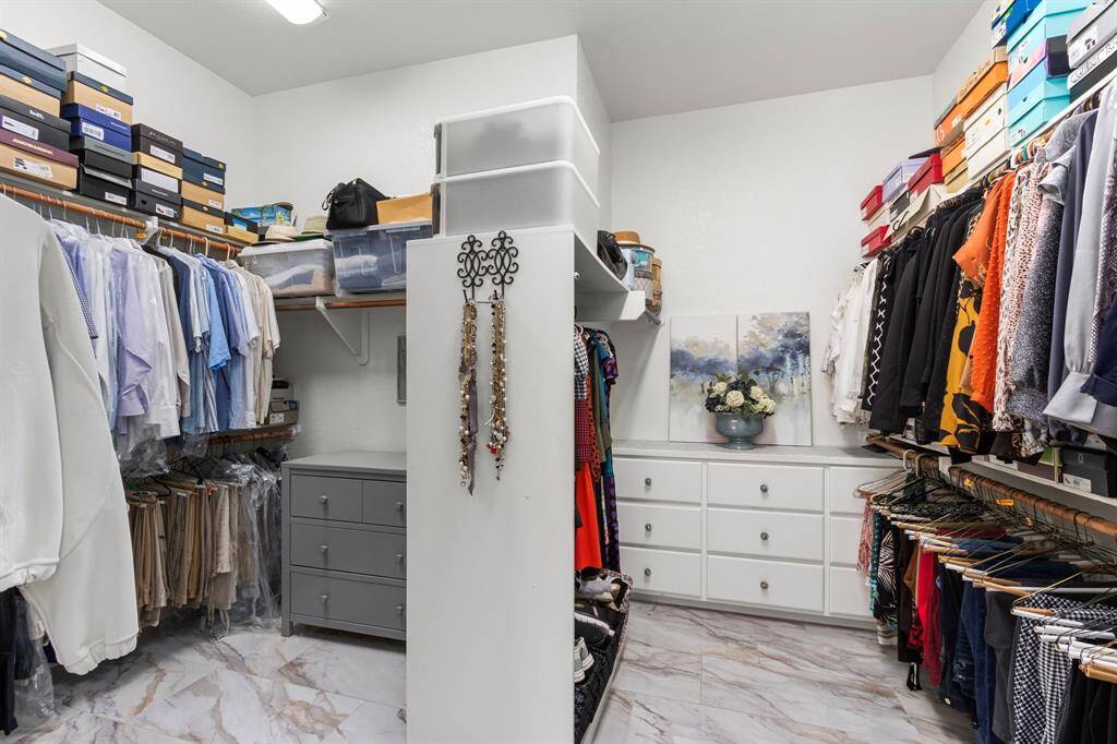 The large two-sided primary closet offers plenty of space for hanging clothing and for storage. This room features automatic lights and the handsome flooring is continued on into this area.