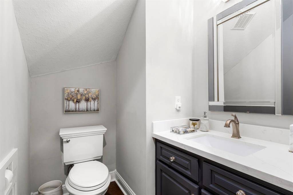 The powder bath that is conveniently located near the main living areas has been completely remodeled with raised-panel vanity topped with quartz and pretty designer mirror.
