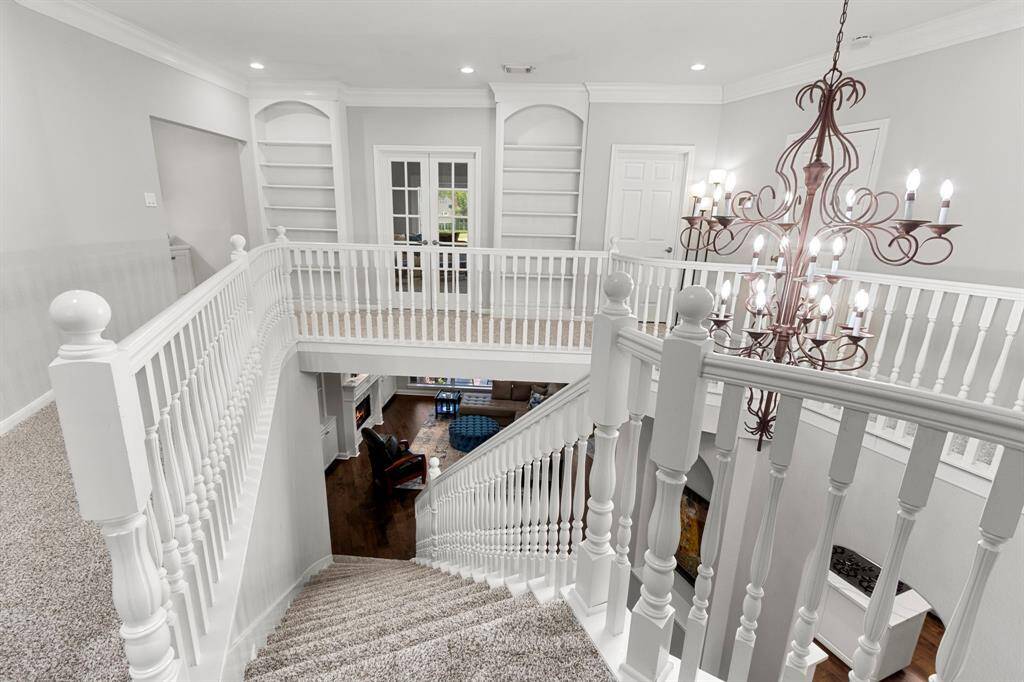 The stairway is pretty with wood newel posts, balusters and handrails. The neutral carpet on the stairway treads continues to the landing and runs throughout the second floor gameroom and bedrooms. Note the pretty designer chandelier that hangs over the entry.