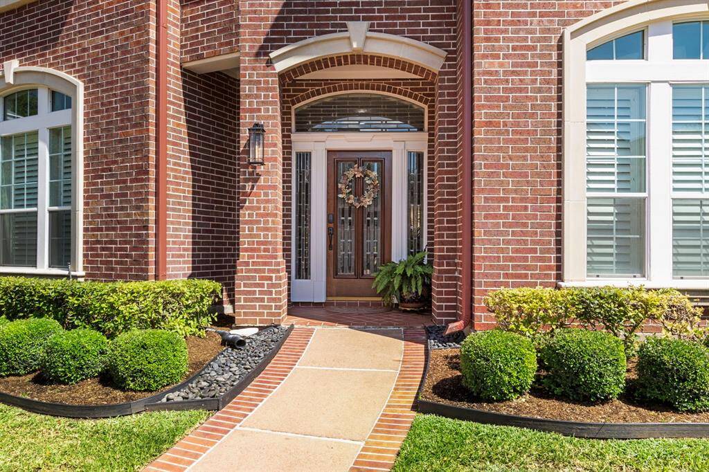 A brick-lined walkway leads from the street to the arched, covered brick porch and beautiful leaded glass front door with side panels and transom window.