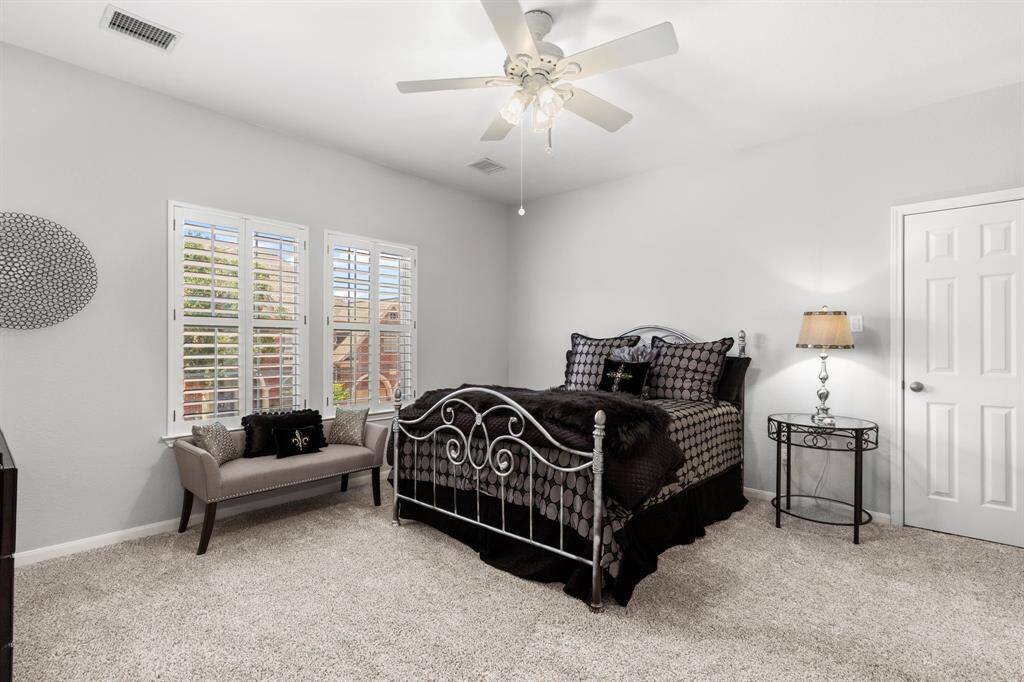 This large secondary bedroom with shuttered windows and large closet shares a Jack-and-Jill bath with another bedroom.