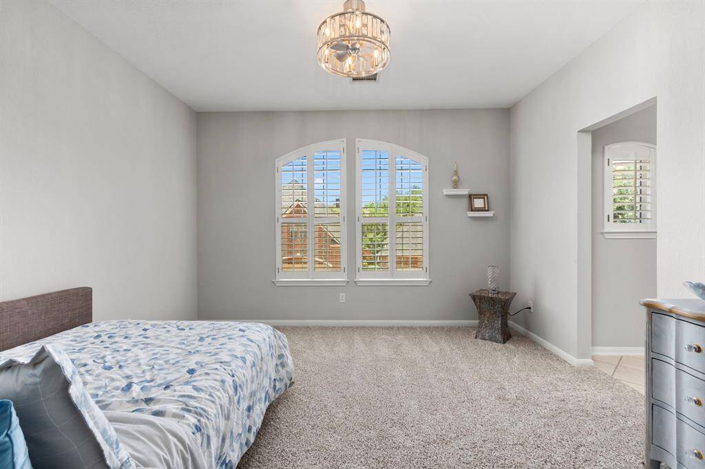 Another pretty bedroom with plantation shuttered windows and designer fan with a peek into its side of the Jack-and-Jill bath.