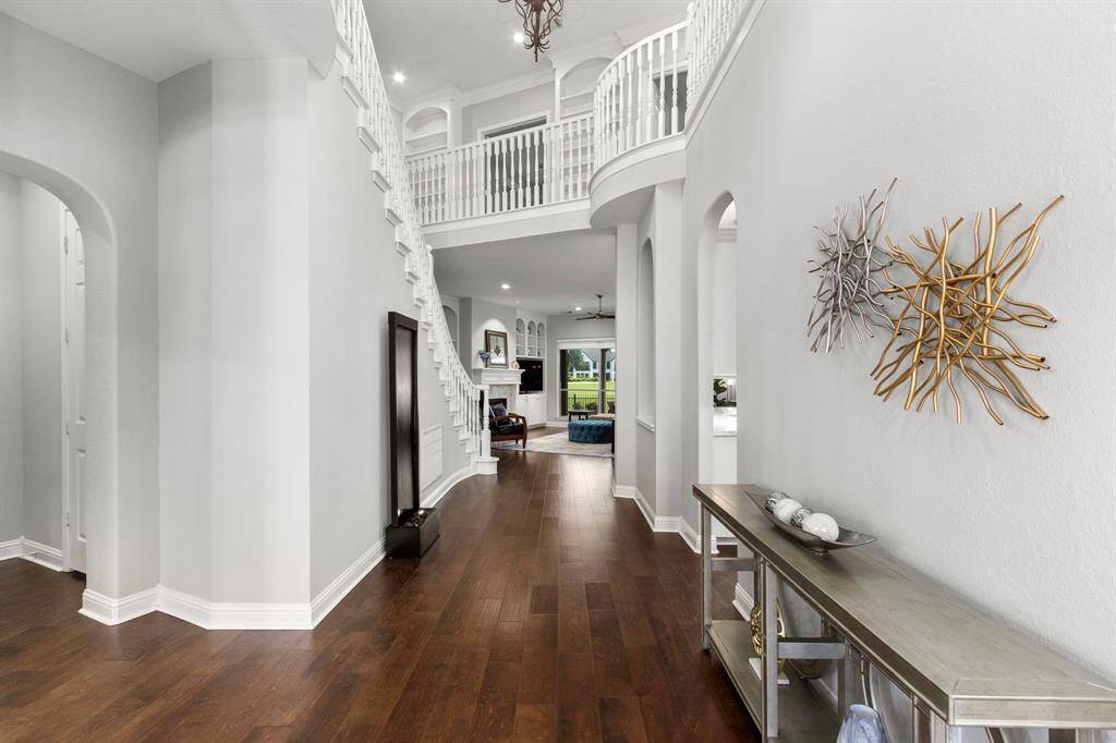 A view down the hallway past the beautiful staircase to the awesome family room . The archway on the left opens to a powder bath and the door to the garage. The kitchen is located on the right. A look up to the second floor landing and you can see beautiful custom built-ins that are located near the gameroom.