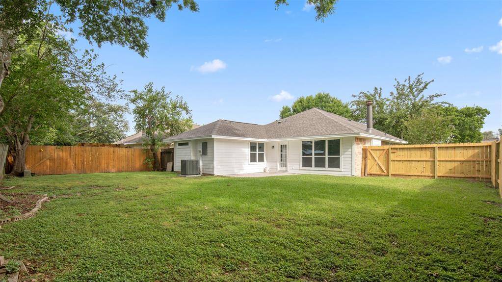 Charming single-story home with a spacious, fenced backyard. Features a well-maintained lawn, large windows, and a patio area, perfect for outdoor activities and entertaining.