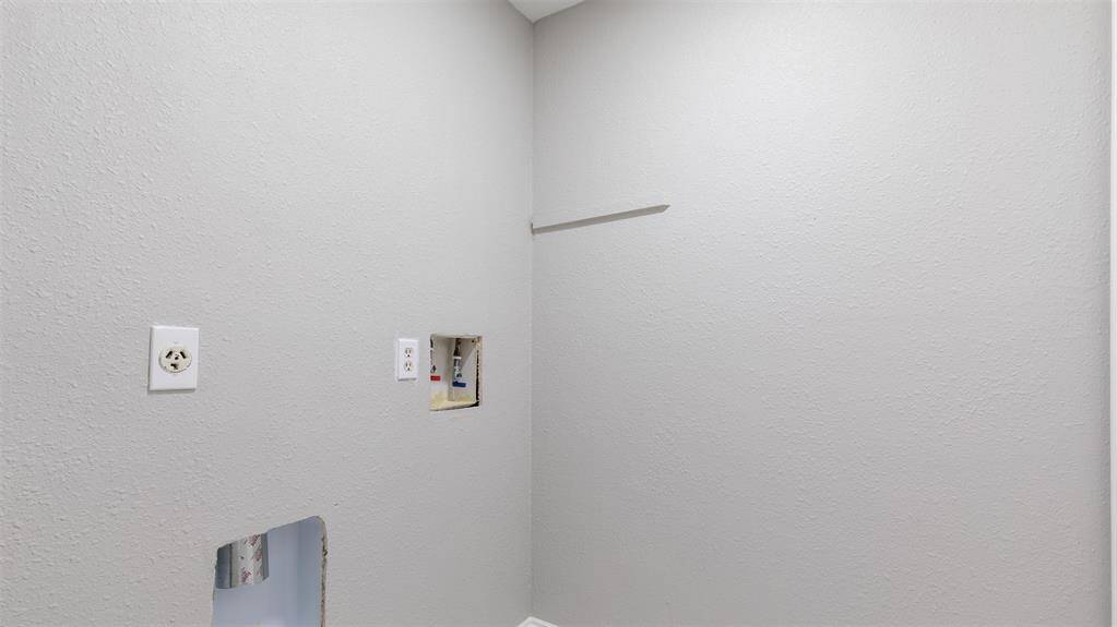 The utility room with hookups for a washer and dryer. The walls are painted a light gray, providing a neutral backdrop.