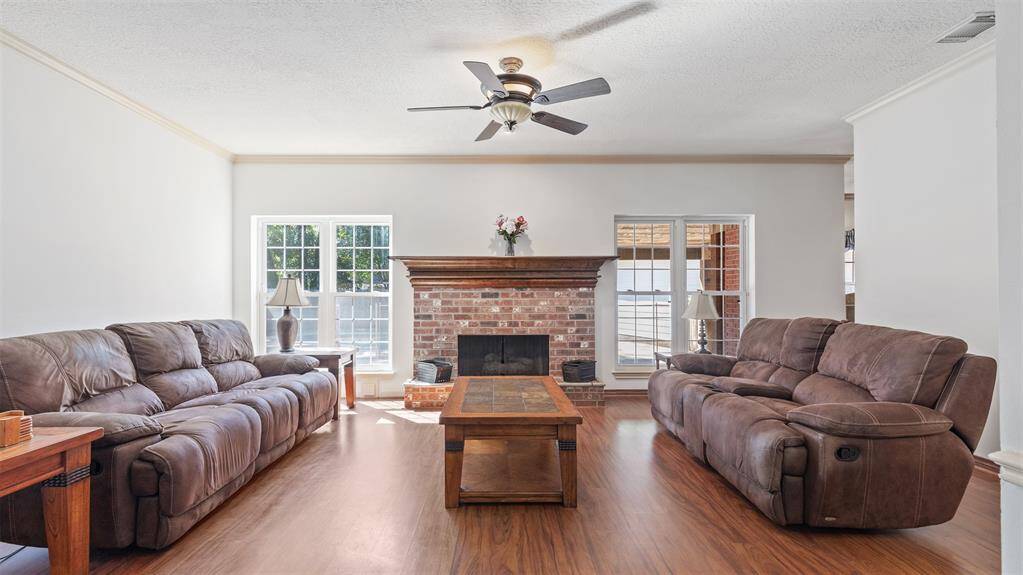 The spacious family room centers around a cozy fireplace, flanked by two large windows that fill the space with natural light. It’s the perfect setting for relaxing evenings or entertaining guests.