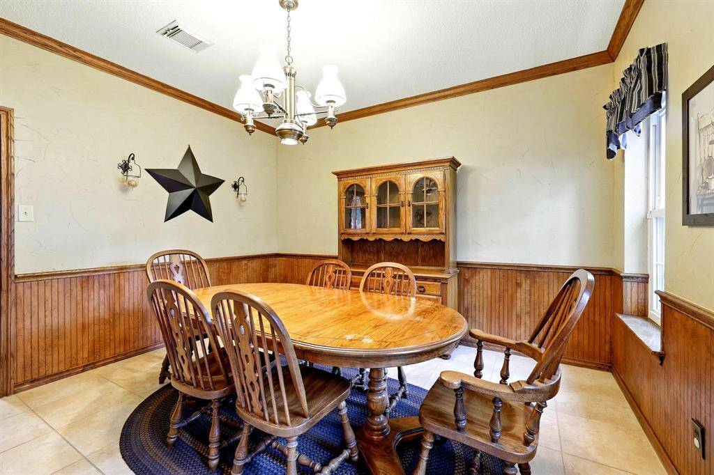 The formal dining room exudes classic charm with beadboard wainscoting, a chair rail, and elegant crown molding that add depth and sophistication.