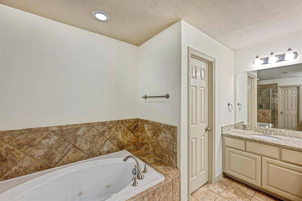 The bathroom is well-lit with recessed ceiling lights and modern wall-mounted fixtures, adding to the overall brightness and warmth of the room.