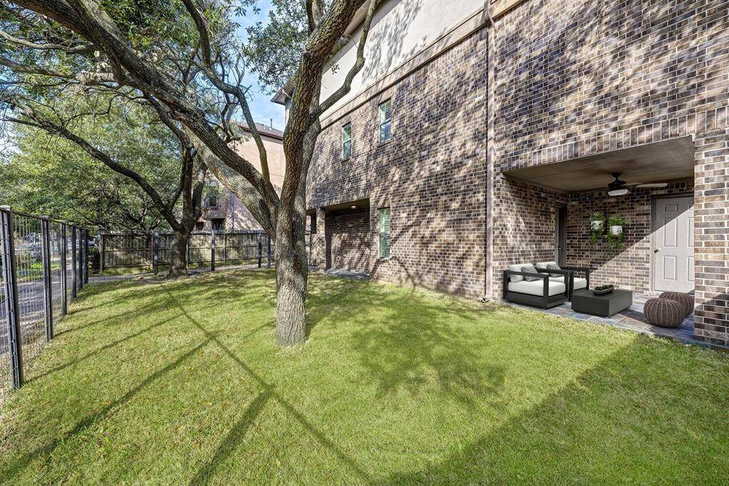 The covered patio offers a cozy outdoor space with a ceiling fan for added comfort during warm weather. The patio floor is laid with textured tiles, providing a durable and stylish surface.