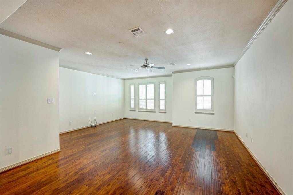 The dining area at features rich hardwood flooring that flows seamlessly into the kitchen space. The room is highlighted by elegant wainscoting and crown molding, which adds a touch of sophistication.