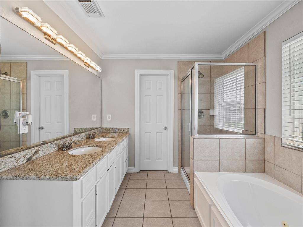 The spa-inspired ensuite bathroom boasts a double vanity, soaking tub, and glass shower.