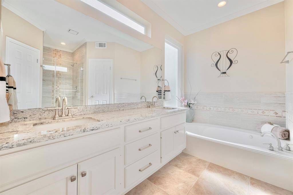 The ensuite primary bath features dual sinks and a soaking tub