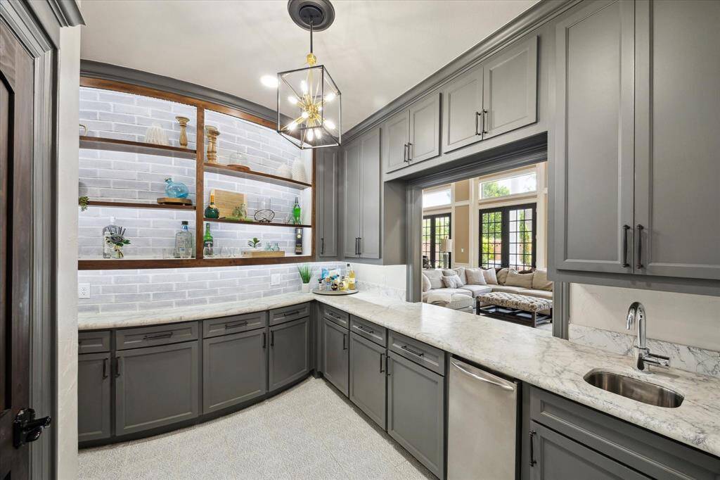 Beautifully designed butler’s pantry with pass through window, open shelving, granite counters that blends both style and functionality, seamlessly transitioning into the Formal dining, family room and kitchen.