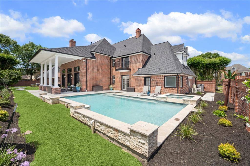 Experience luxury outdoor living in this resort-style backyard retreat. Perfectly designed for relaxation and entertaining. The sparkling custom pool with spa takes center stage, bordered by elegant stone coping and enhanced by lush landscaping and manicured flower beds.