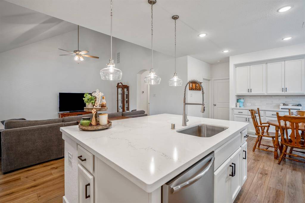 From this vantage point, you can appreciate the open flow between the kitchen, living, and dining spaces. The single basin stainless steel sink with an upgraded pull-out faucet and built-in dishwasher in the island offer both functionality and style. Just beyond the dining area, you'll find convenient access to the garage and a storage closet, adding to the home's practical design.