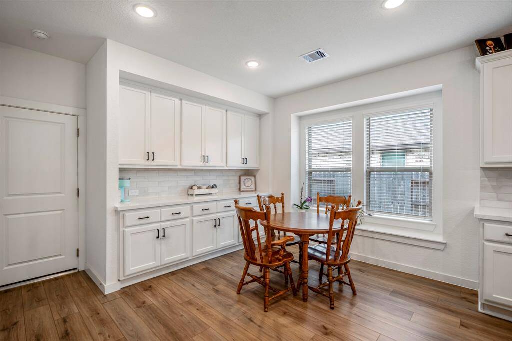 The dining area features a beautiful wall of cabinetry along the far side, providing ample storage space and adding a touch of elegance to the room. The large double windows bring in plenty of natural light, and the built-in window seat offers a cozy spot to relax while enjoying the view of the backyard. This charming space is perfect for everyday meals or entertaining guests.