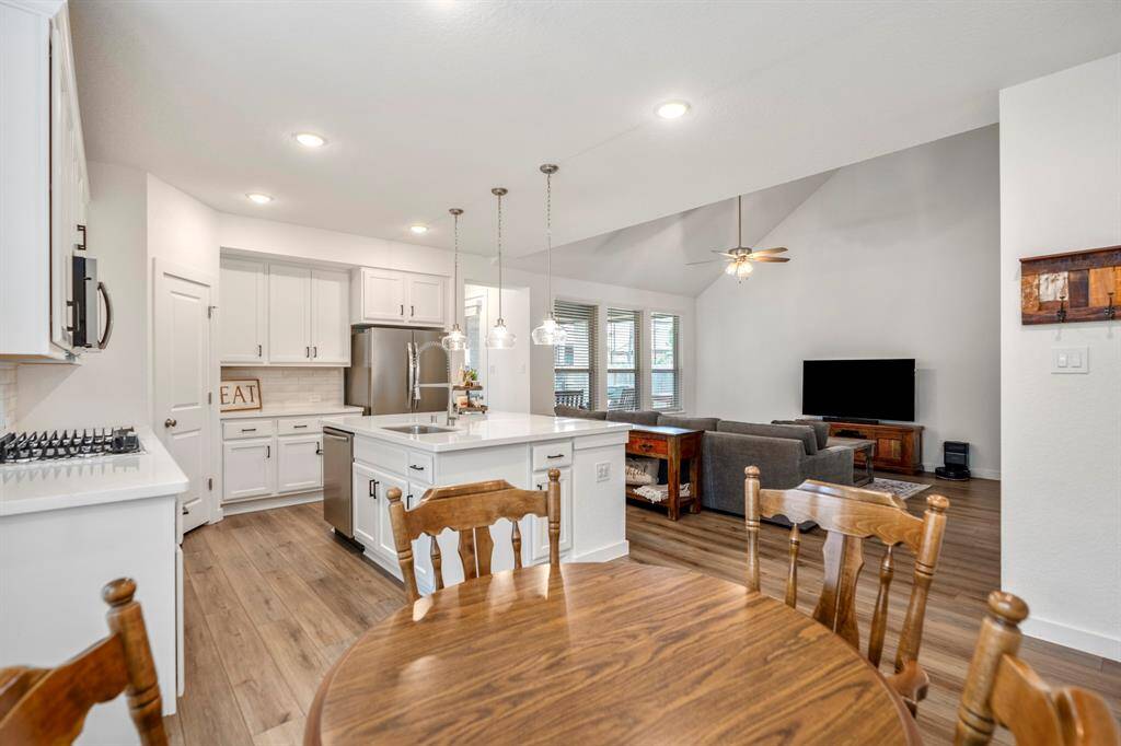 From this corner of the dining room, you can see the open layout that connects the kitchen to the living room. The kitchen, with its oversized island and ample cabinetry, is just to the left, while the living room beyond offers views of the expansive backyard. This layout creates a bright and airy space, perfect for both everyday living and entertaining.