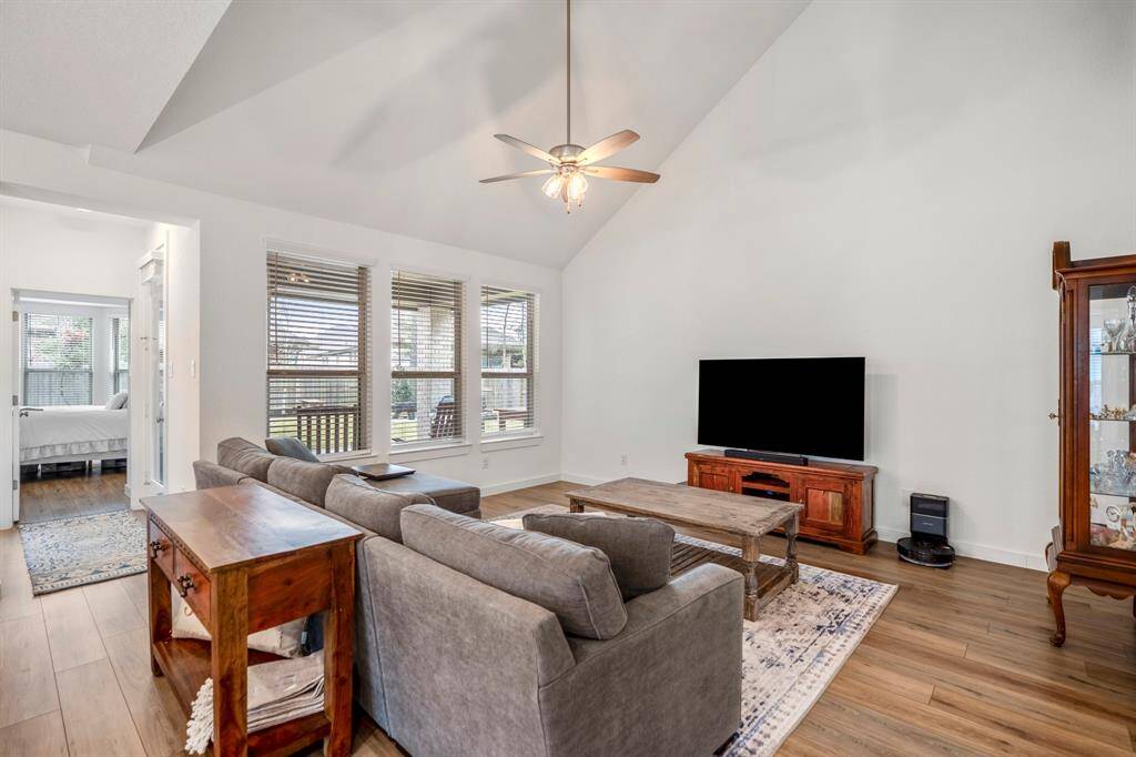 As you move back toward the living room from the dining area, this view highlights the spaciousness of the open-concept design. The living room is bathed in natural light, offering a welcoming atmosphere. To the left, the hallway provides a glimpse into the private primary suite, adding an element of privacy and convenience to the home’s layout.