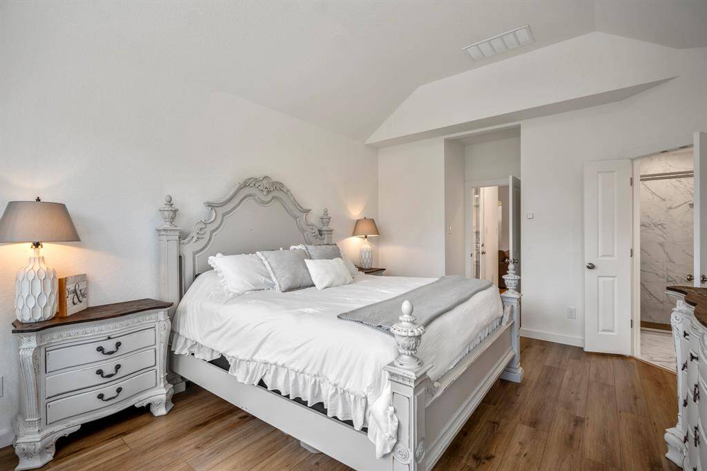 From this angle, the primary suite offers a peaceful view with the bay windows drawing in natural light. The doorway to the left leads back to the living areas, with easy access to the patio through the back door in the hallway. On the right, double doors open into the luxurious primary bathroom, completing this private retreat.