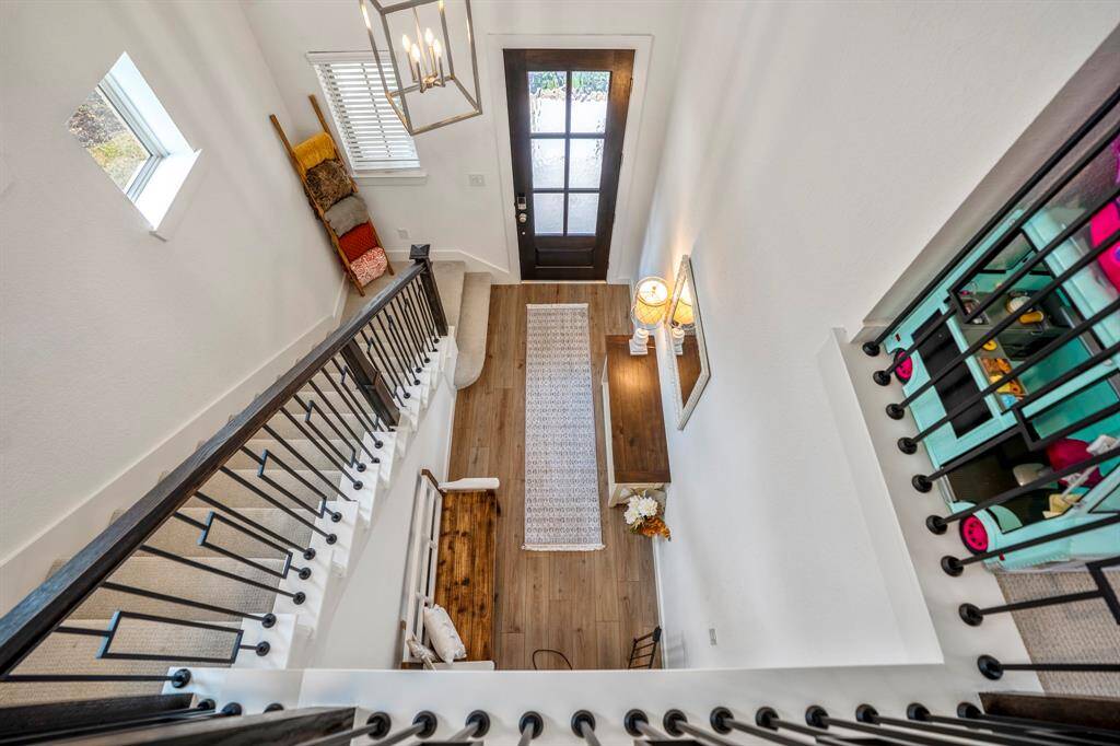 From the landing above, this view overlooks the grand foyer, showcasing the open and airy design of the home. The staircase below adds architectural charm, while the soaring ceilings enhance the sense of space. The natural light filtering through the entryway creates a bright and welcoming atmosphere.