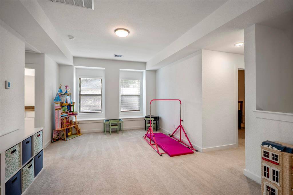 At the top of the stairs, the loft-style game room greets you with its open, versatile space. Perfect for relaxation or entertainment, this area offers plenty of room for activities, while the high ceilings and natural light create an inviting atmosphere. The space is designed to fit various needs, whether it's a game room, media room, or home office.