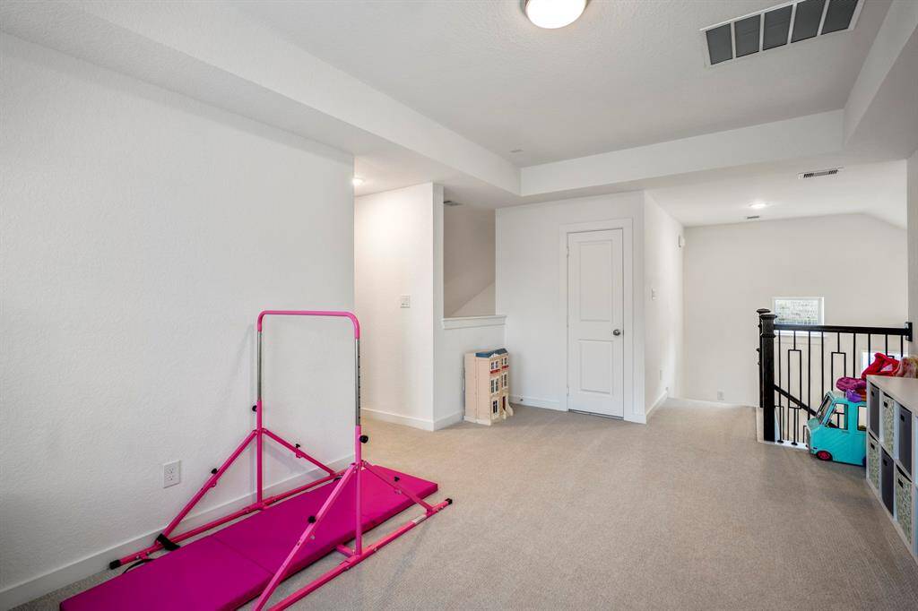 From the game room, looking back at the staircase, the layout of the second floor becomes clear. To the right, just out of view, is a bedroom and bath, providing privacy and convenience. The hallway to the left leads to the media room/office space and another bedroom with a bath. A doorway just beside the staircase opens to attic space. The open design of the game room ties everything together, creating a spacious and functional upper level.