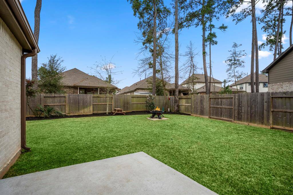 Looking out into the yard from the patio, you can see the cozy firepit area tucked into the corner, perfect for gathering with friends and family. The expansive yard offers plenty of room for outdoor activities, while the firepit adds a charming and inviting focal point to the space.