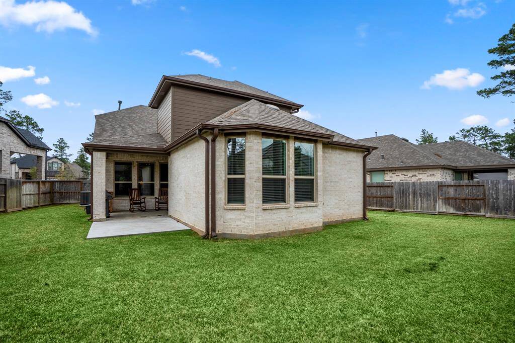 Standing near the firepit, looking back at the house, you can see how the yard wraps around the home, offering plenty of space for outdoor enjoyment. The large yard provides both privacy and room for various activities, with the house providing a beautiful backdrop to this expansive outdoor area.