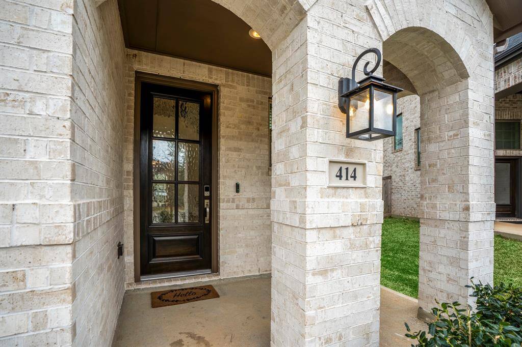 The inviting front porch, framed by elegant double arches, leads to a stunning glass front door that fills the entryway with natural light. A warm and welcoming first impression awaits.