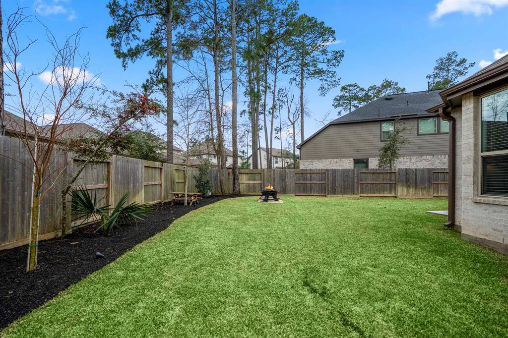 Looking across the backyard, the rear fenceline is to the left, with the firepit directly ahead and the house to the right. The landscaped areas along the fence add a touch of greenery, while the picnic table area within that space provides an ideal spot for outdoor dining or relaxation. This layout offers a perfect blend of functionality and tranquility, making it a wonderful space for entertaining or unwinding.