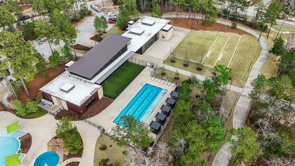 This view from behind the amenities center in The Woodlands Hills offers a great perspective of the expansive resort-style pool and surrounding facilities. From this angle, you can see how seamlessly the building blends with the lush landscaping, creating a serene and inviting space. With walking trails nearby and the pavilion offering shade, it’s an ideal spot for both relaxation and community events.
