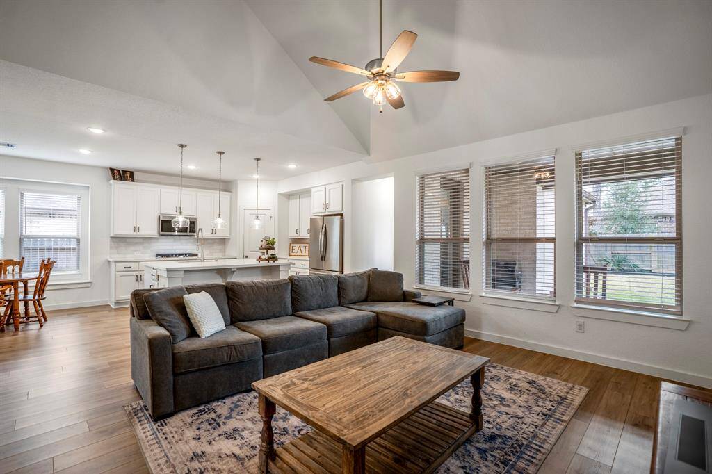 This view highlights the seamless flow between the living room, kitchen, and dining area. The open layout creates a bright and spacious feel, perfect for gathering and entertaining. The kitchen, with its oversized island and abundant storage, serves as the heart of the home, while the dining area offers a welcoming space for meals and conversation.