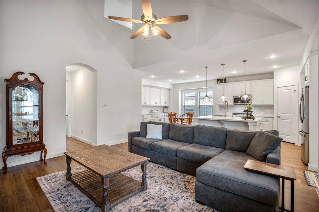 This perspective captures the full flow of the open-concept design, seamlessly connecting the living room, kitchen, and dining area. The wall of cabinetry in the dining space provides ample storage and versatility, perfect for a coffee or wine bar. A glimpse of the second-floor loft above adds to the home's spacious and airy feel, while the arched doorway leads back to the grand foyer.