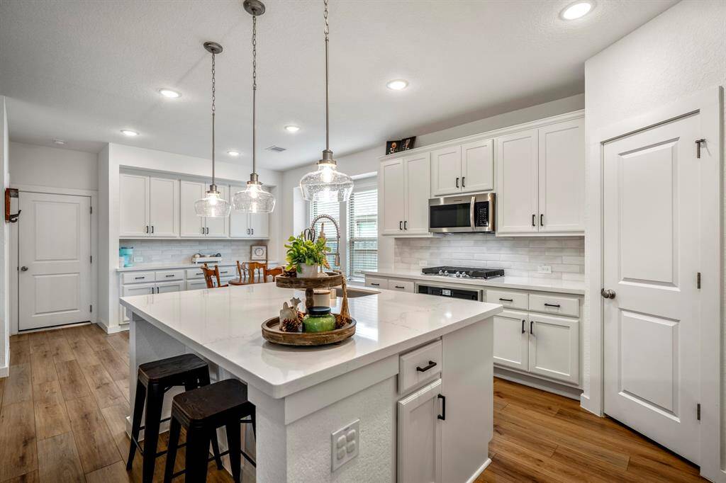 Standing near the oversized island, this view showcases the true scale of the kitchen's centerpiece. With additional storage on each side, gleaming quartz countertops, and a convenient breakfast bar, this kitchen is both functional and stylish. The abundance of natural light creates a bright and inviting atmosphere, making it the perfect space for both cooking and entertaining.