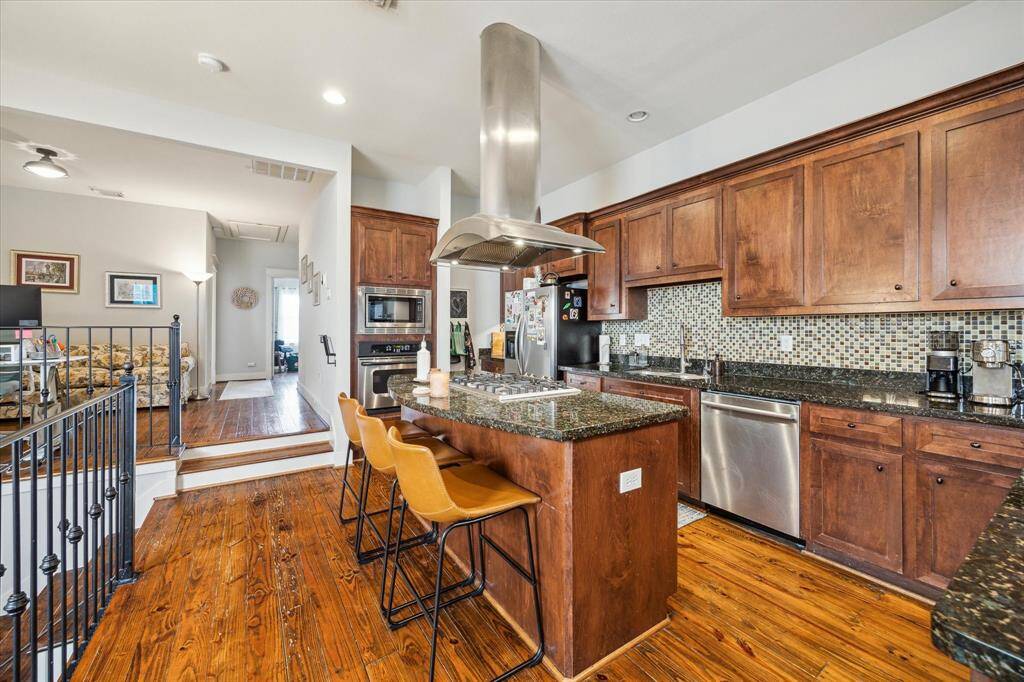 Discover a spacious kitchen featuring elegant wood cabinetry, a central island with seating, and modern stainless steel appliances. Ideal for culinary enthusiasts and entertaining.