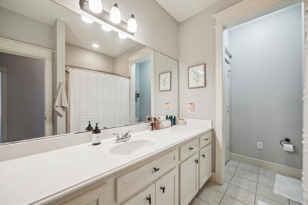 Elegant secondary bathroom featuring a spacious vanity, modern fixtures, and ample lighting—perfect for guests or family.