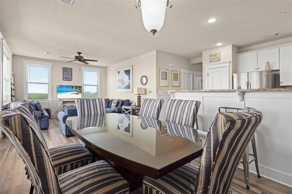 The space features a charming wooden table, complemented by a stunning chandelier that adds a touch of sophistication. Large windows flood the room with natural light, highlighting the serene ocean views.