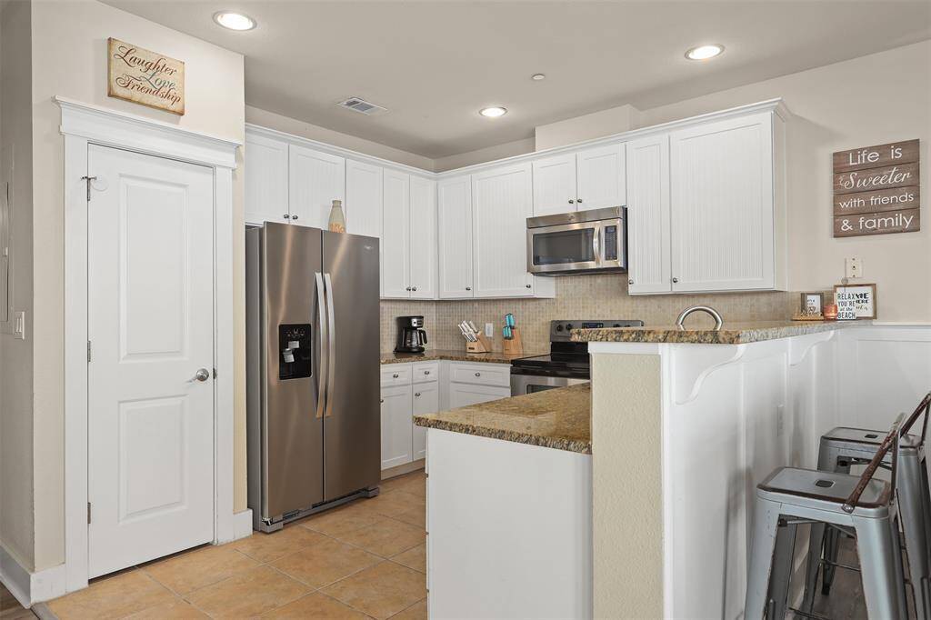 Welcome to your dream kitchen! This beautifully designed space features modern stainless steel appliances, pristine white cabinetry, and granite counters complimented by an elegant tile backsplash.