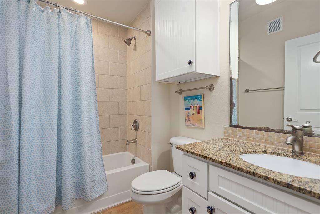 Charming and functional, this guest bathroom features a fresh coastal theme and vibrant decor. The clean granite vanity offers ample counter space and storage, complemented by a large mirror that enhances the room's brightness.