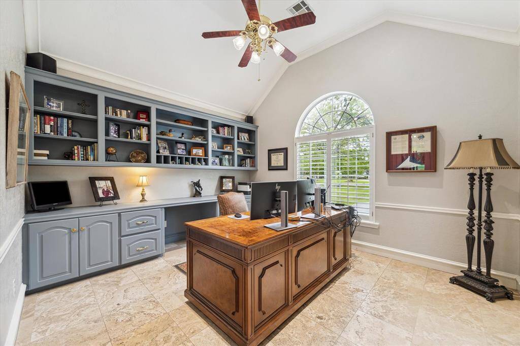 The home office is located in a quiet space on the opposite side of the family room and kitchen. Travertine stone floors contrast well with the neutral wall paint. Ample built in storage provides lots of options for supplies.