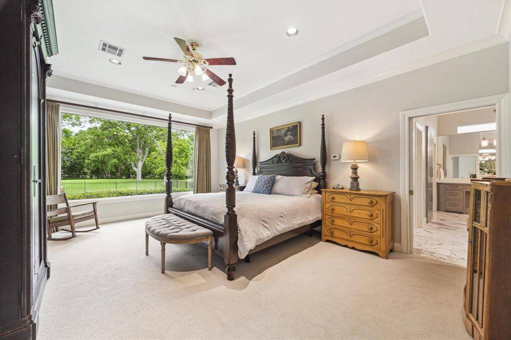 The primary suite overlooks the back yard through this large window. The tray ceiling adds drama to this serene setting.