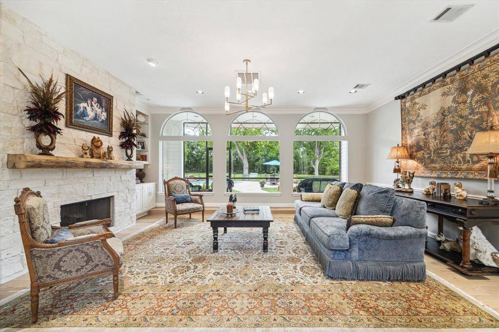 The formal living room is the first place your guests will see when they enter the front door. Arched picture windows provide a clear view of the expansive back yard and pool area. The Austin limestone fireplace surround and antique barn wood mantle set the mood for the room. Equipped with gas logs and connection, this fireplace can also accommodate wood burning fires.