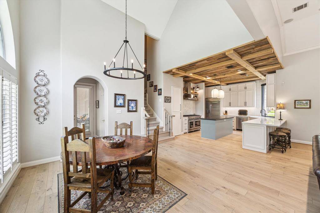 The breakfast area is nestled under a 17 foot cathedral ceiling. The chandelier is one of many that were replaced during the renovation. Through the arched opening is a beautiful half bath and entry to the screened in porch.
