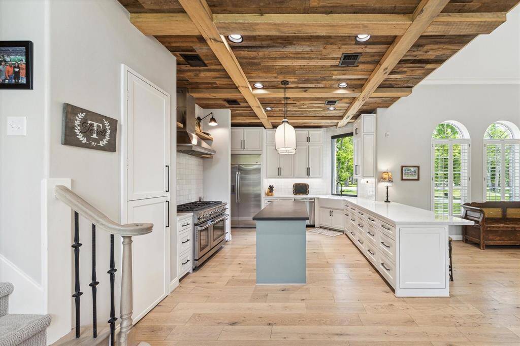 This vantage point of the kitchen really accentuates the custom ceiling. The soft close cabinets and drawers result in less noise. Under cabinet lighting is one of several layers of illumination in the kitchen. Just beyond the banister to the back set of stairs is the walk in pantry space.