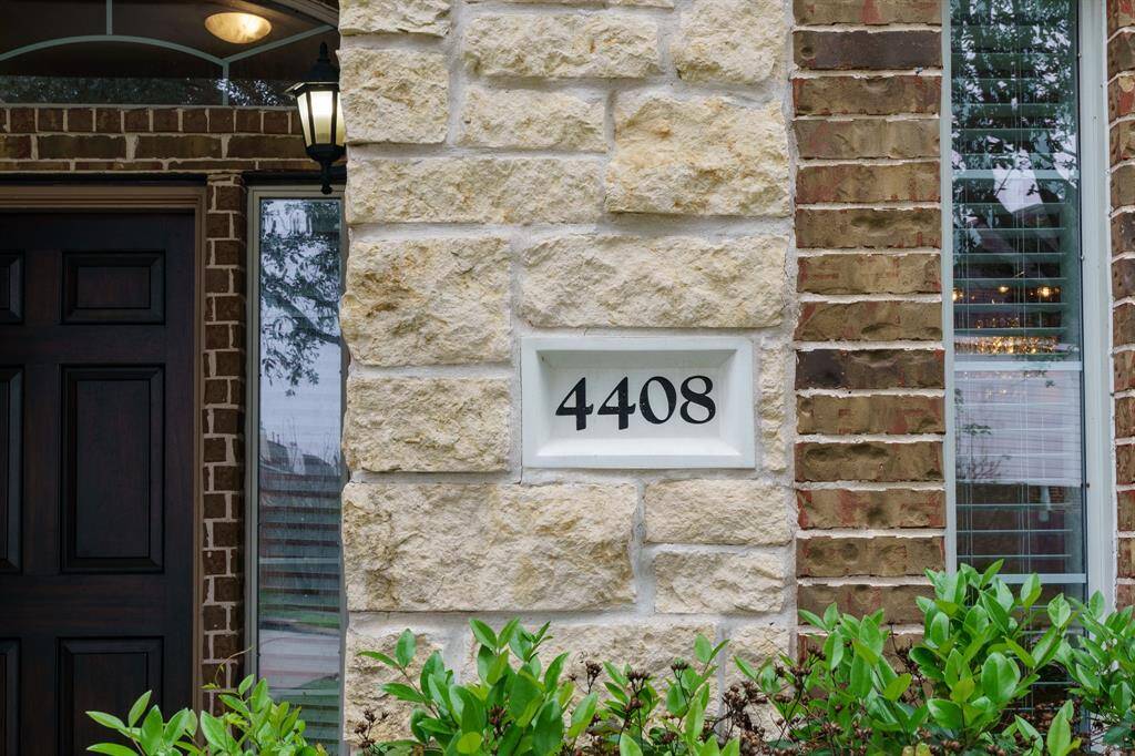 The photo shows a home's entrance with a dark wooden door, stone and brick exterior, house number "4408," and nearby greenery. A lantern-style light fixture adds charm.