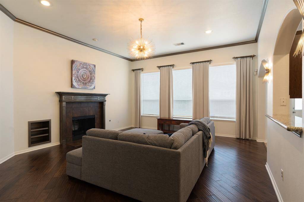 Chic and inviting living area with elegant wood floors, a cozy fireplace, and abundant natural light through large windows.