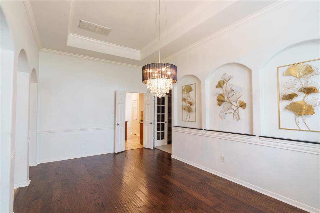 Bright Dining Room featuring hardwood floors, elegant tray ceiling, large windows with natural light, and stylish wall niches for decor.